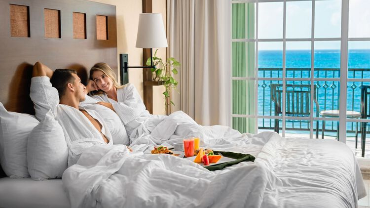 Habitación con vista al mar para dos personas en la cama disfrutando del desayuno